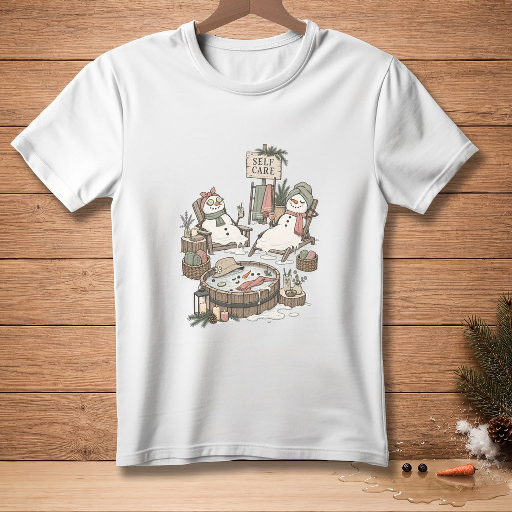 White t-shirt with a drawing of snowmen enjoying a spa day, labeled "Self Care".