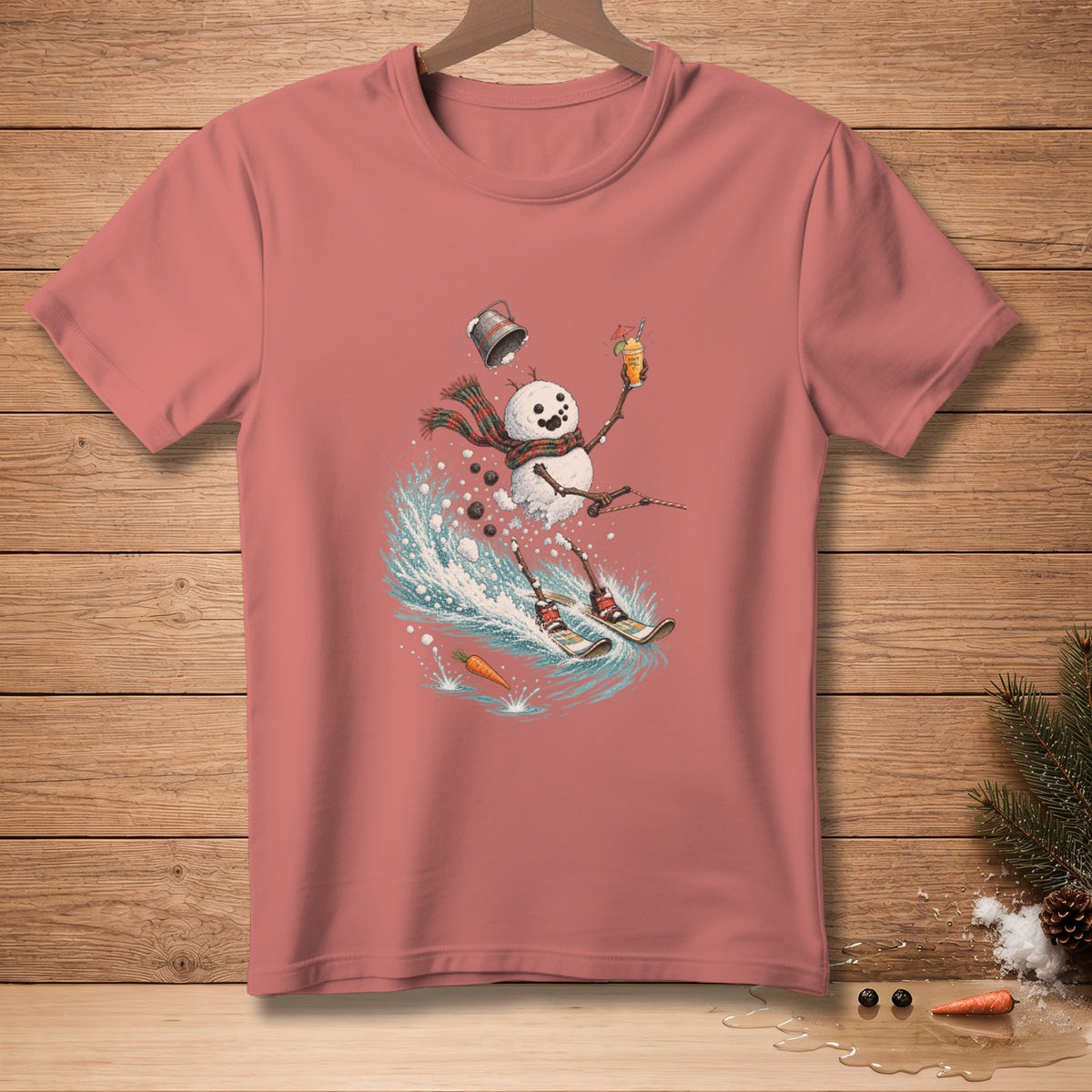 Snowman skiing with drink, wearing scarf, on salmon pink t-shirt.