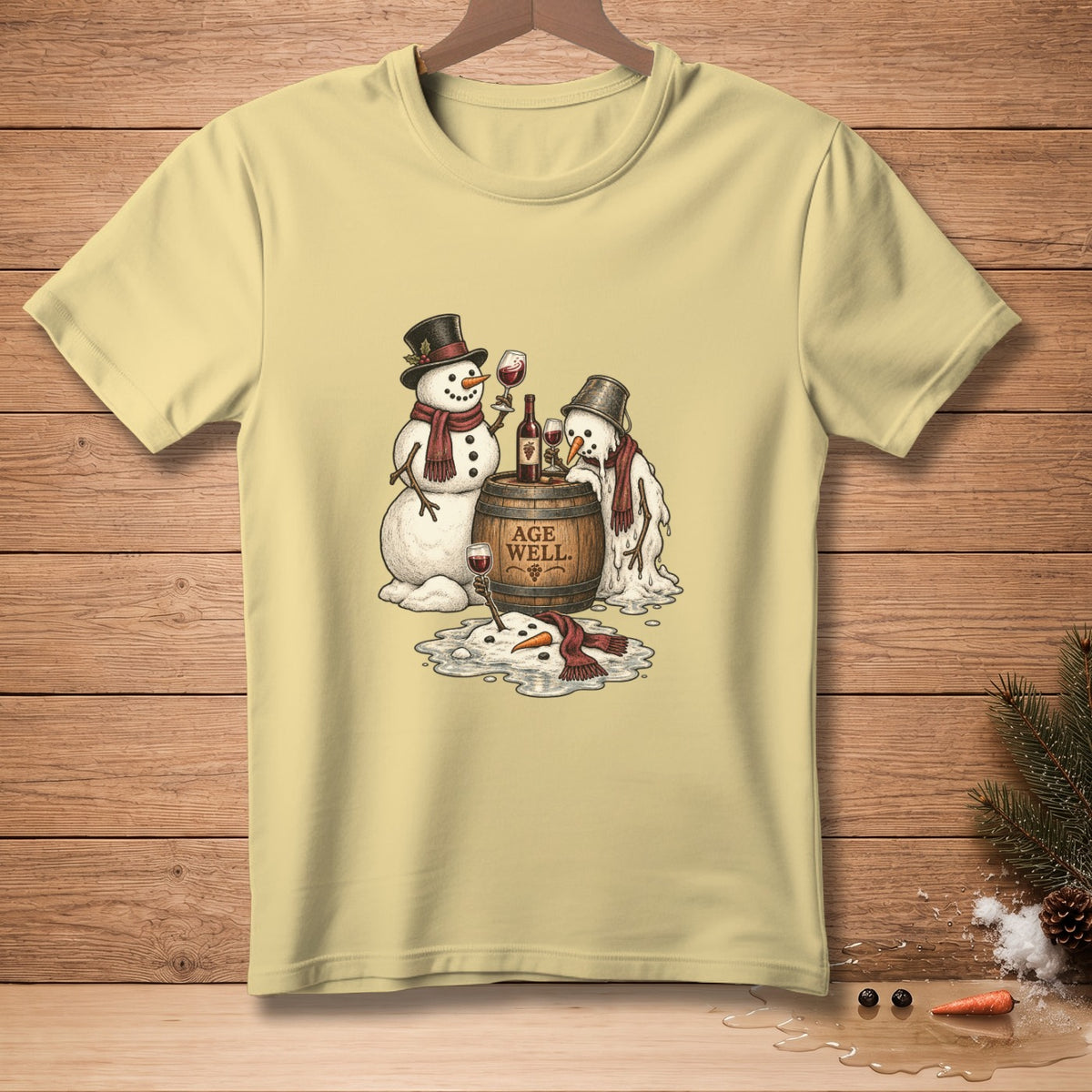 Yellow t-shirt with snowmen, wine, and "Age Well" text on a barrel.